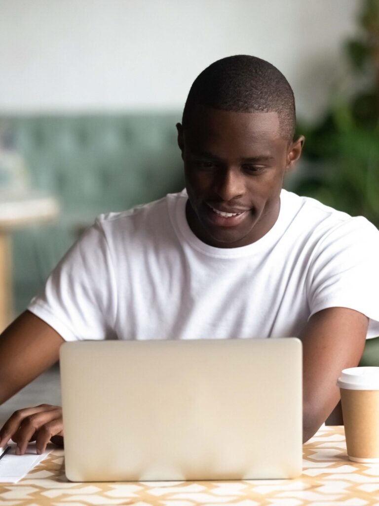 Smiling African American man using laptop, making notes